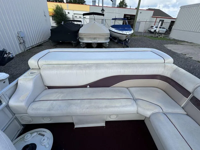 Slide: The Image of 2001 Godfrey Sweetwater boat interior with white and maroon seating, parked near other boats. - 6