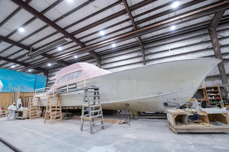 Slide: The Image of 2024 Custom Carolina 63 yacht under construction in a spacious indoor facility. - 2