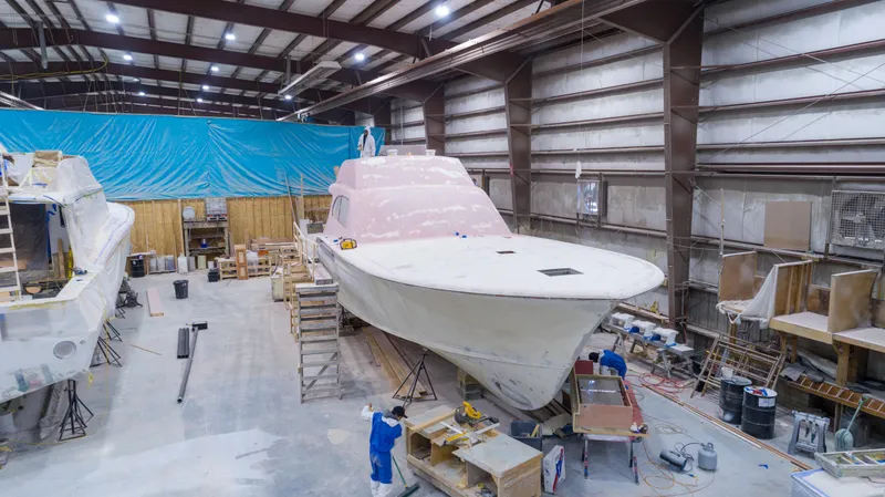Slide: The Image of 2024 Custom Carolina 63 yacht under construction in a large indoor facility. - 49