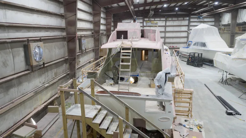 Slide: The Image of 2024 Custom Carolina 63 yacht under construction in a spacious indoor facility. - 9