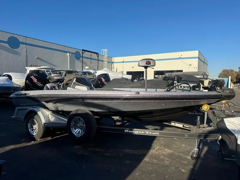 Slide: The Image of 2024 Ranger Z518 boat on trailer, parked outdoors under clear blue sky. - 0