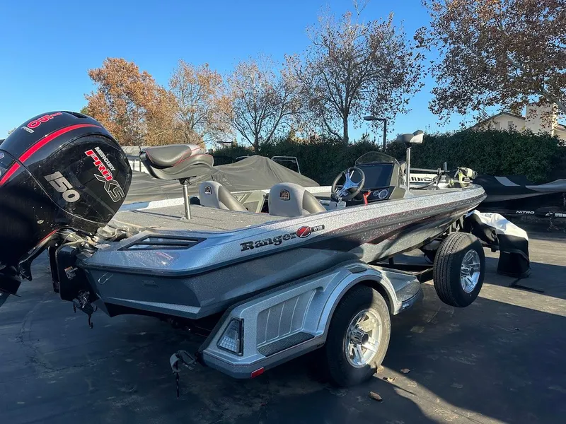 Slide: The Image of 2024 Ranger Z518 boat on trailer with 150 horsepower engine, parked outdoors. - 2