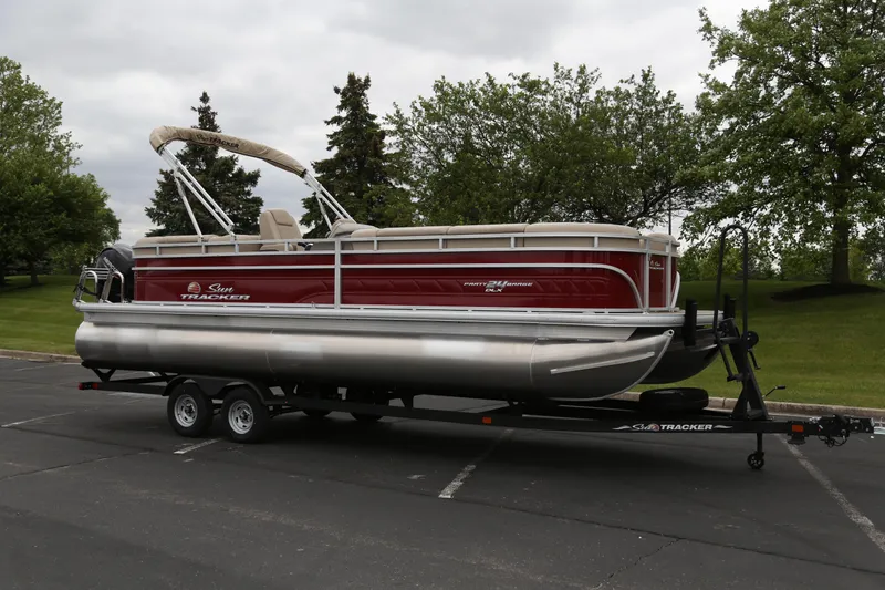 The Image of 2024 Sun Tracker Party Barge 24 DLX pontoon boat on trailer in parking lot. - 0