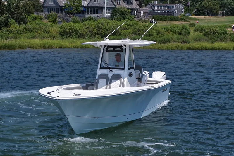 Slide: The Image of 2025 Regulator 28 boat cruising on a scenic waterway near coastal homes. - 4