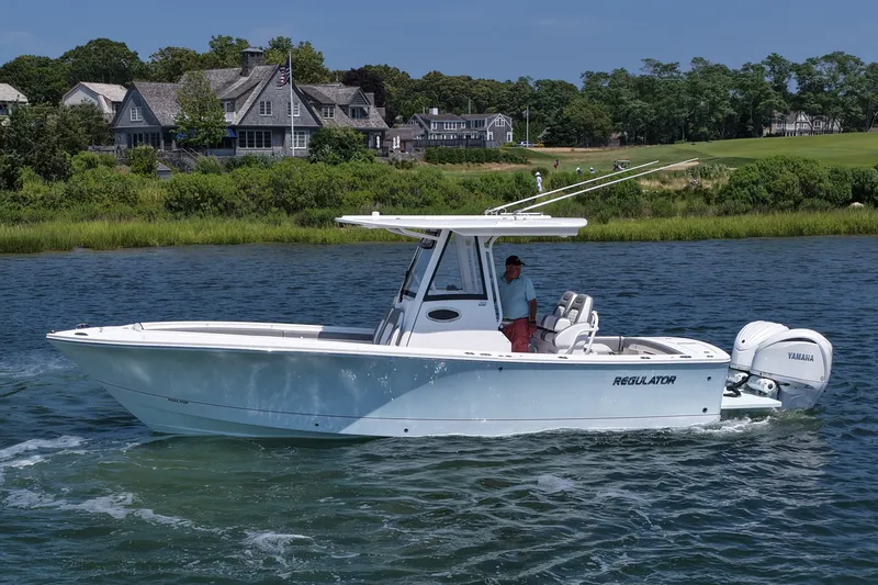 Slide: The Image of 2025 Regulator 28 boat cruising on water near coastal homes. - 6