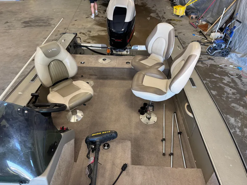Slide: The Image of 2002 Lund 1775 Pro-V SE boat interior with seating and motor in a garage setting. - 13