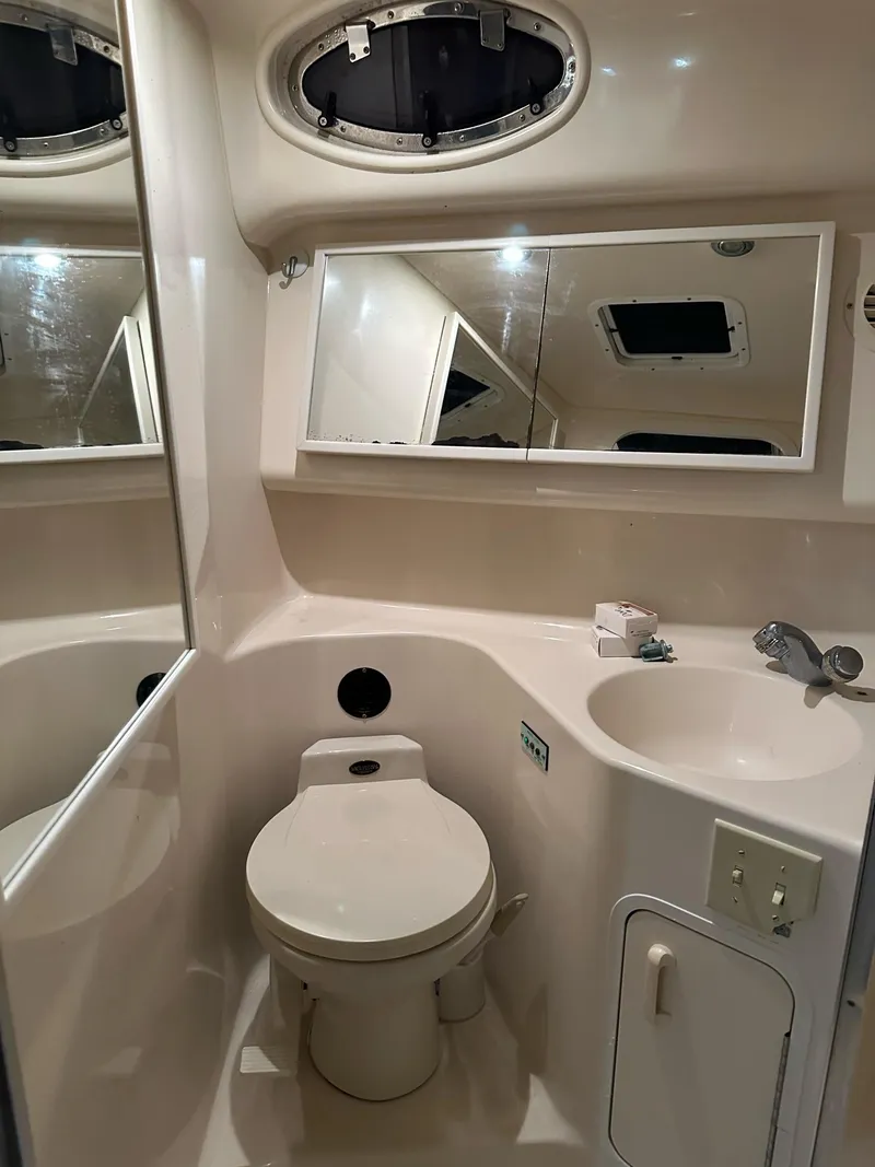 Slide: The Image of 1997 Sea Ray 370 Sundancer bathroom with toilet, sink, and mirrored cabinet. - 16