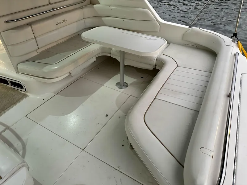 Slide: The Image of 1997 Sea Ray 370 Sundancer interior with white seating and table, near water. - 8