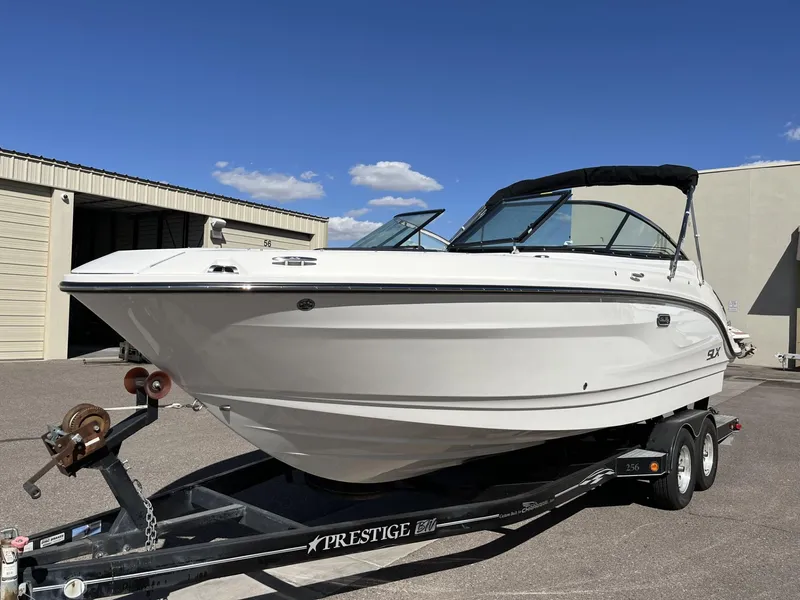 Slide: The Image of 2024 Sea Ray SLX 260 boat on a trailer in a sunny outdoor setting. - 52