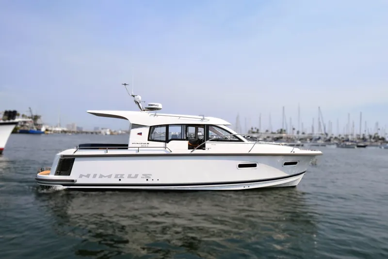 Slide: The Image of 2024 Nimbus 305 Coupe yacht on calm water with marina background. - 1