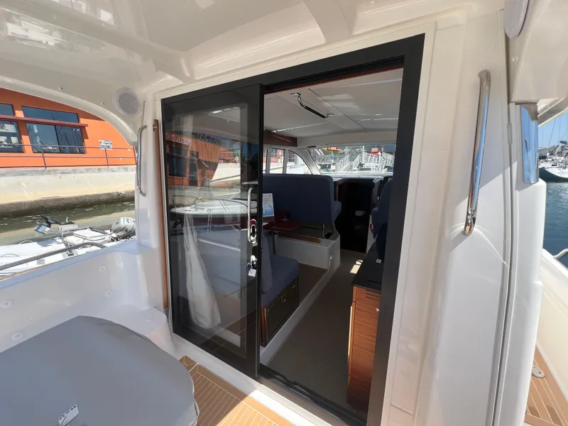 Slide: The Image of 2024 Nimbus 305 Coupe interior view with sliding glass door and marina backdrop. - 10