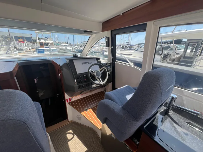 Slide: The Image of Interior of 2024 Nimbus 305 Coupe, featuring helm and seating area in a marina setting. - 14