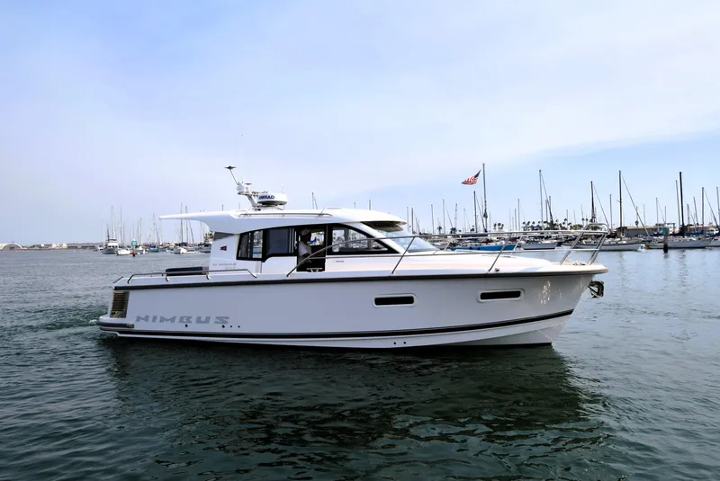 Slide: The Image of 2024 Nimbus 305 Coupe yacht cruising in a marina with sailboats in the background. - 3