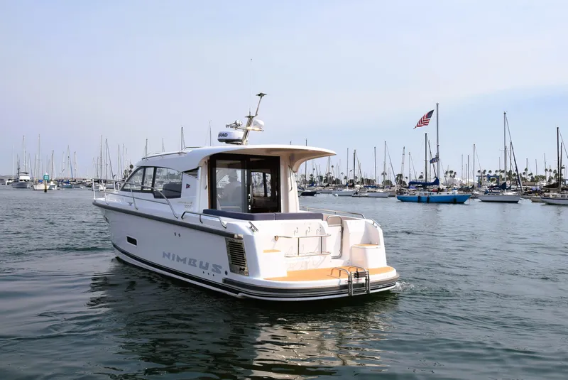 Slide: The Image of Nimbus 305 Coupe 2024 in a marina, surrounded by sailboats and calm waters. - 4