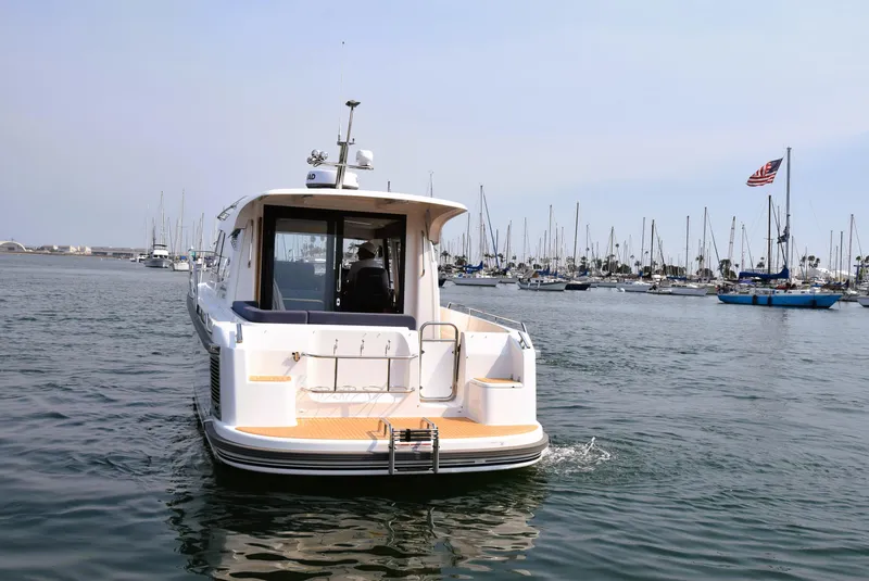 Slide: The Image of Nimbus 305 Coupe 2024 cruising in a marina with sailboats in the background. - 5