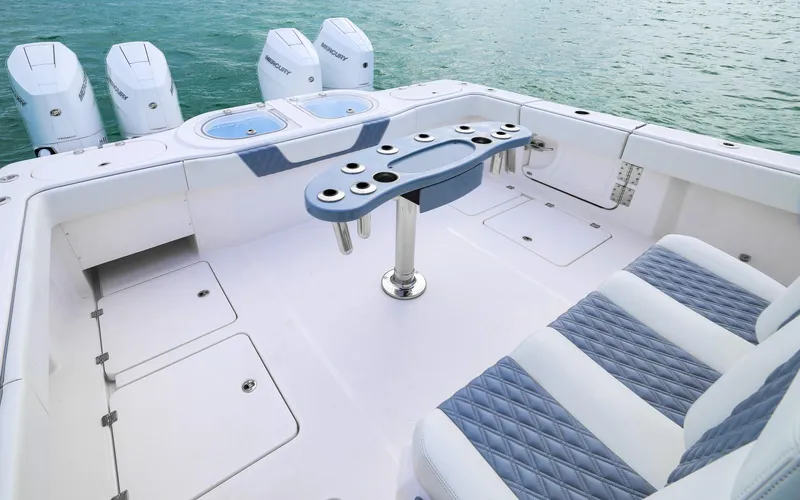 Slide: The Image of 2024 Invincible 46 Catamaran deck with seating, rod holders, and outboard engines on the water. - 24