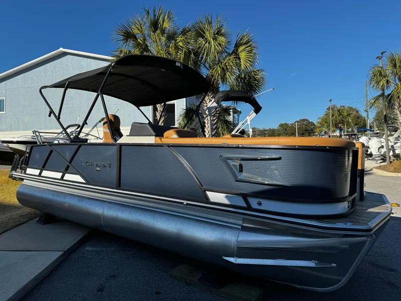 The Image of 2024 Crest Caribbean LX 230 pontoon boat with black canopy and palm trees in the background. - 0