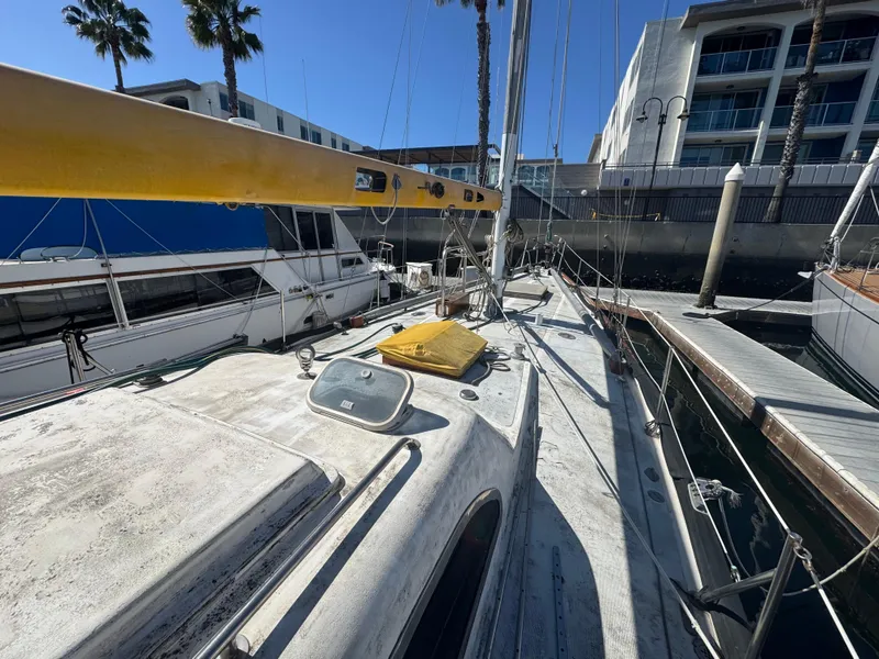 Slide: The Image of 1967 Columbia Yacht 50 docked, showing deck and mast, with nearby boats and buildings. - 3