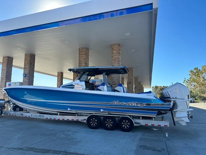 Slide: The Image of 2024 Nor-Tech 400 Supersport boat on a trailer at a gas station. - 19