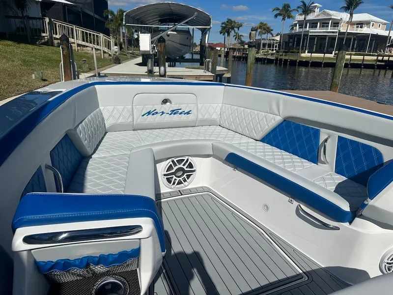 Slide: The Image of 2024 Nor-Tech 400 Supersport boat interior with blue and white seating, docked by waterfront homes. - 22