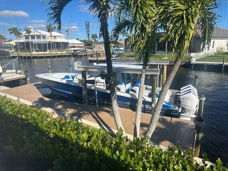 Slide: The Image of 2024 Nor-Tech 400 Supersport boat docked by a canal with palm trees. - 31