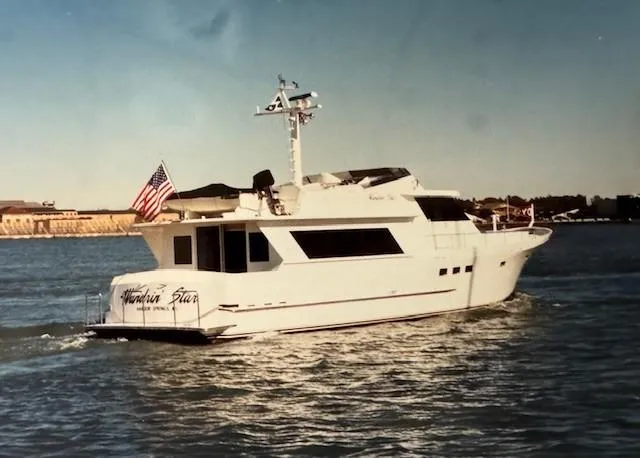 Slide: The Image of 1990 Motor Yacht 70 Brata cruising on open water, American flag displayed. - 11