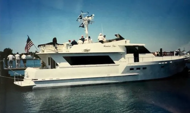 Slide: The Image of 1990 Motor Yacht 70 Brata docked, featuring sleek design and American flag. - 12