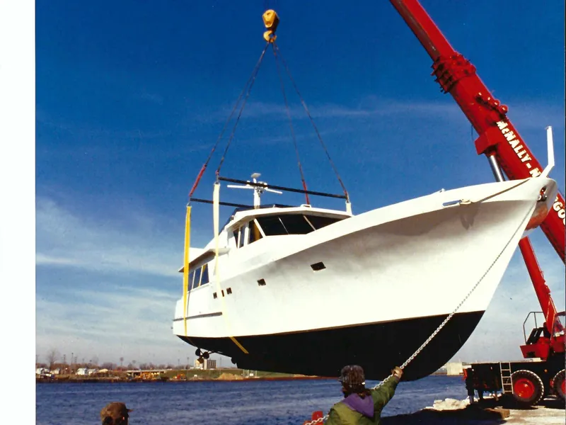 Slide: The Image of Crane lifting 1990 Motor Yacht 70 Brata over water under clear blue sky. - 14