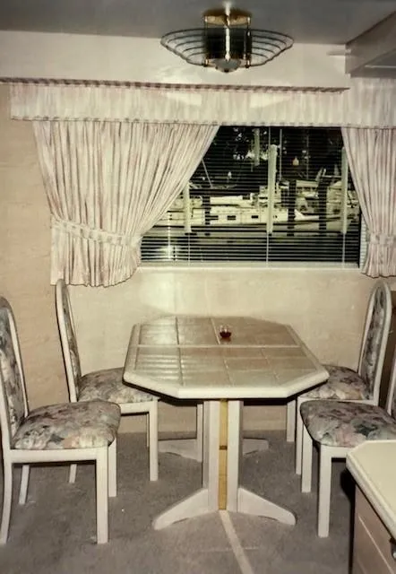 Slide: The Image of Dining area in 1990 Motor Yacht 70 Brata with table, chairs, and window view. - 24