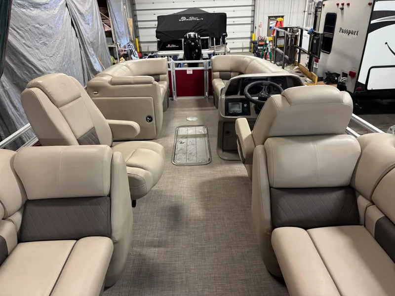 Slide: The Image of 2024 Sun Tracker Party Barge 22 XP3 interior with beige seating in a garage setting. - 12