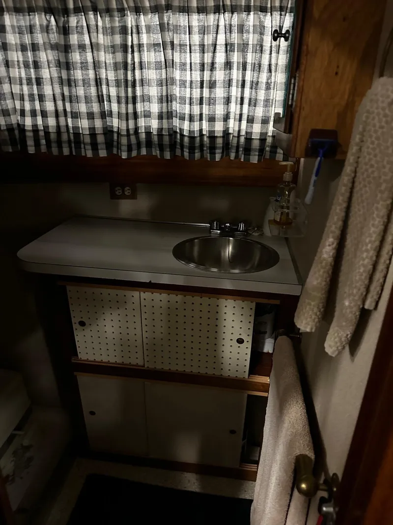 Slide: The Image of 1975 Marinette 32' Cruiser bathroom with sink, checkered curtains, and wooden cabinetry. - 27