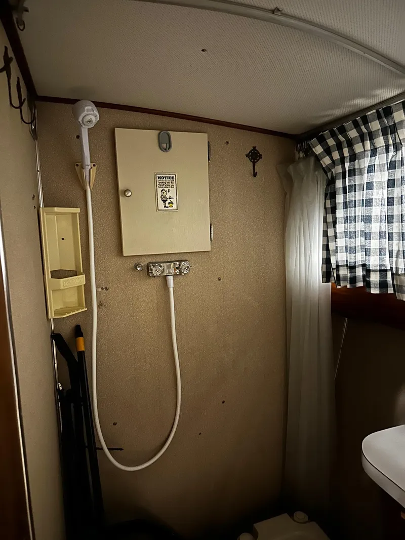 Slide: The Image of 1975 Marinette 32' Cruiser bathroom with shower, vintage decor, and checkered curtain. - 28