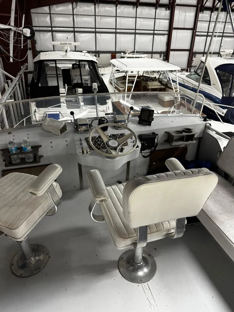 Slide: The Image of 1975 Marinette 32' Cruiser helm with dual seats in a boat storage facility. - 29