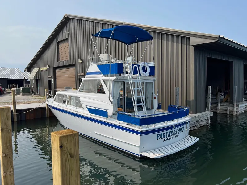 Slide: The Image of 1975 Marinette 32' Cruiser docked near a boathouse, featuring blue and white design. - 4