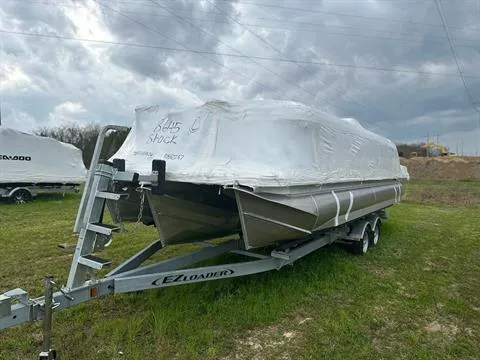The Image of 2024 Manitou 24 Explore pontoon boat on E-Z Loader trailer, covered in protective wrap. - 0