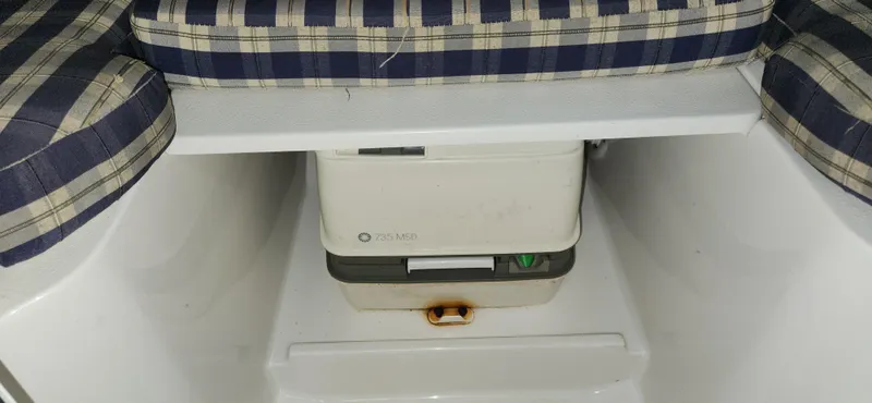 Slide: The Image of 2004 Chris-Craft Corsair 25 boat interior with plaid cushions and storage compartment. - 19