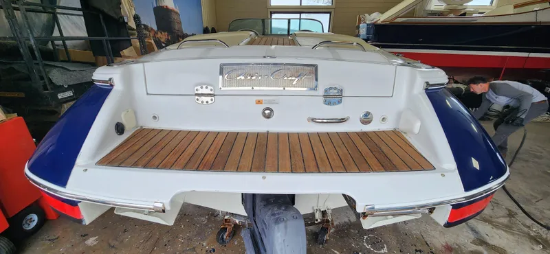 Slide: The Image of 2004 Chris-Craft Corsair 25 boat rear view with teak swim platform in a garage. - 27
