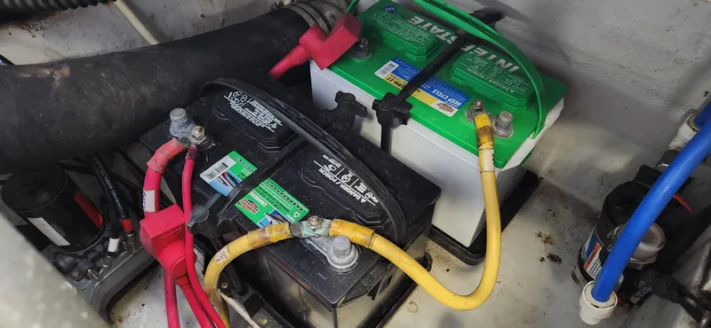 Slide: The Image of 2004 Chris-Craft Corsair 25 boat battery compartment with two batteries and connected cables. - 29