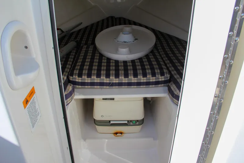 Slide: The Image of 2004 Chris-Craft Corsair 25 cabin interior with plaid cushions and portable toilet. - 38