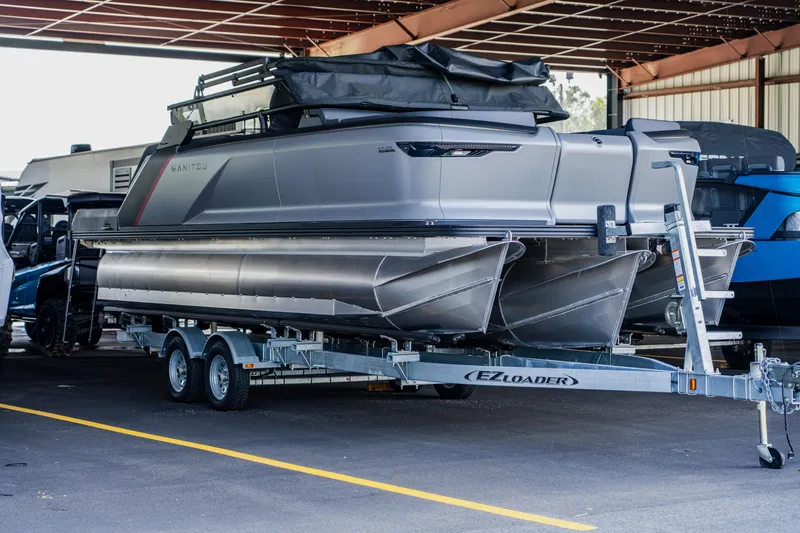 The Image of 2023 Manitou 22 EXPLORE BENCH pontoon boat on trailer in covered storage. - 0