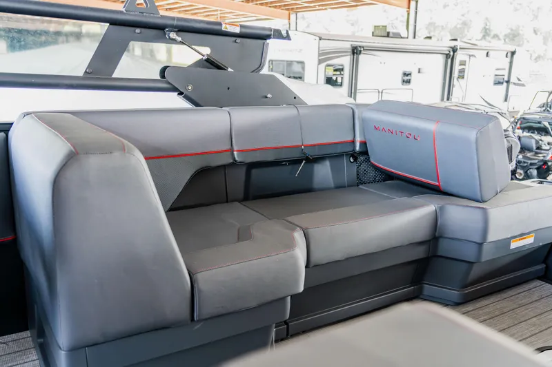 Slide: The Image of 2023 Manitou 22 Explore Bench boat interior with gray seating and red accents. - 5