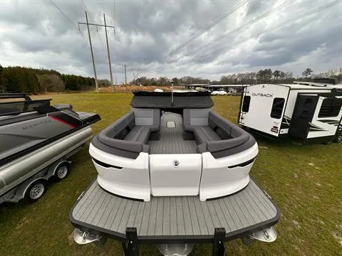 Slide: The Image of 2024 Manitou 24 Explore pontoon boat with spacious seating, parked outdoors. - 1