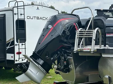 Slide: The Image of 2024 Manitou 24 Explore boat engine with Outback RV in the background. - 2