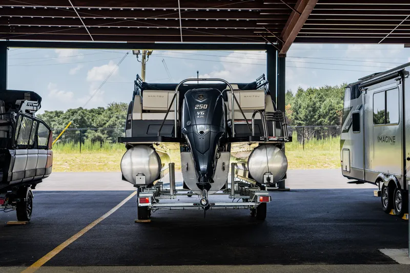 Slide: The Image of 2024 Manitou 26 Explore SHP575 Switchback pontoon boat on trailer, rear view. - 1