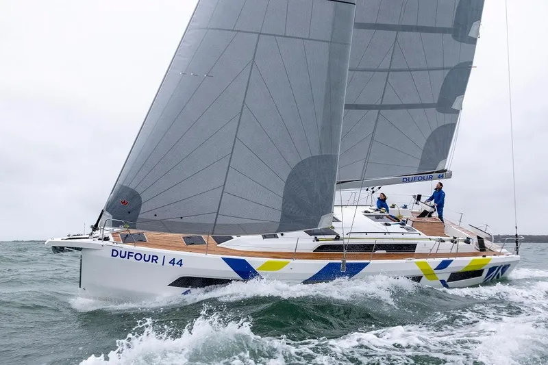 Slide: The Image of 2024 Dufour 44 sailboat navigating through waves. - 2