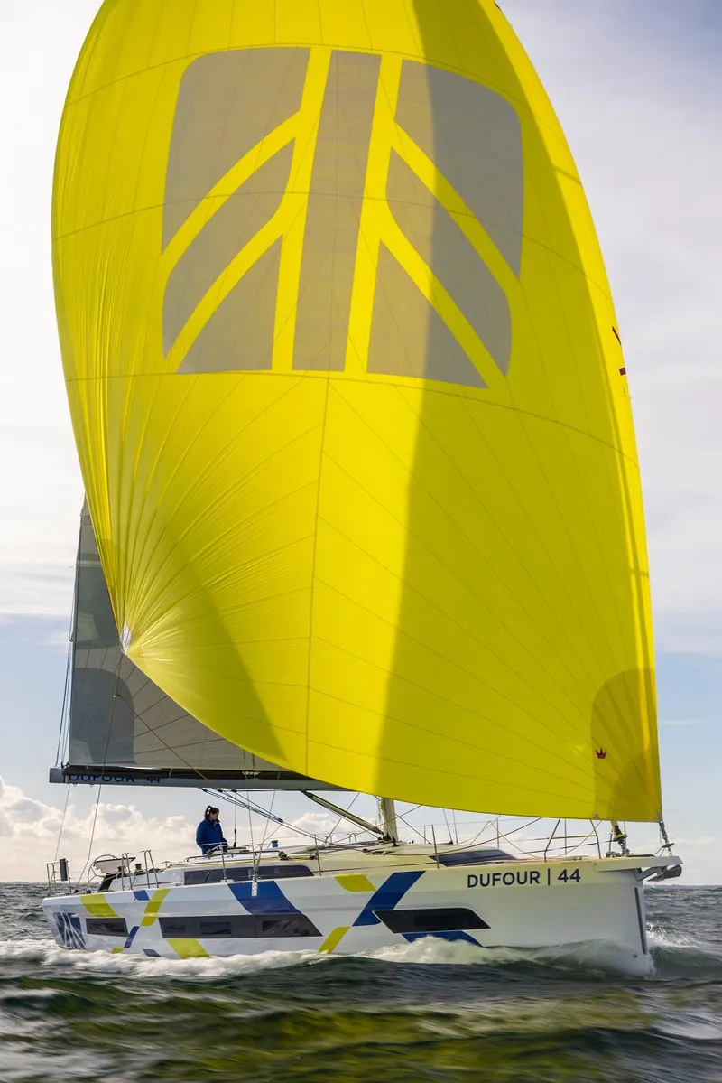 Slide: The Image of 2024 Dufour 44 sailboat with a vibrant yellow sail on open water. - 16