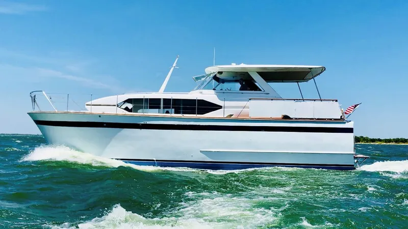 The Image of 1969 Chris-Craft 46 Roamer yacht cruising on open water under a clear blue sky. - 0