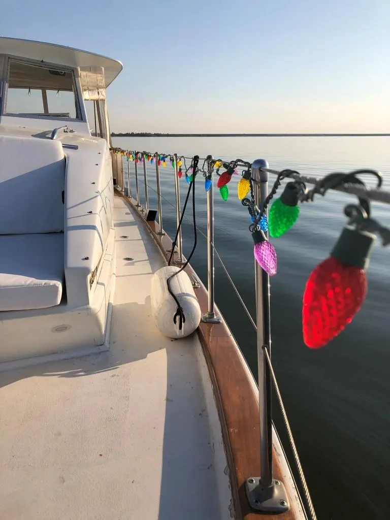 Slide: The Image of 1969 Chris-Craft 46 Roamer decorated with colorful lights on a calm waterway. - 13