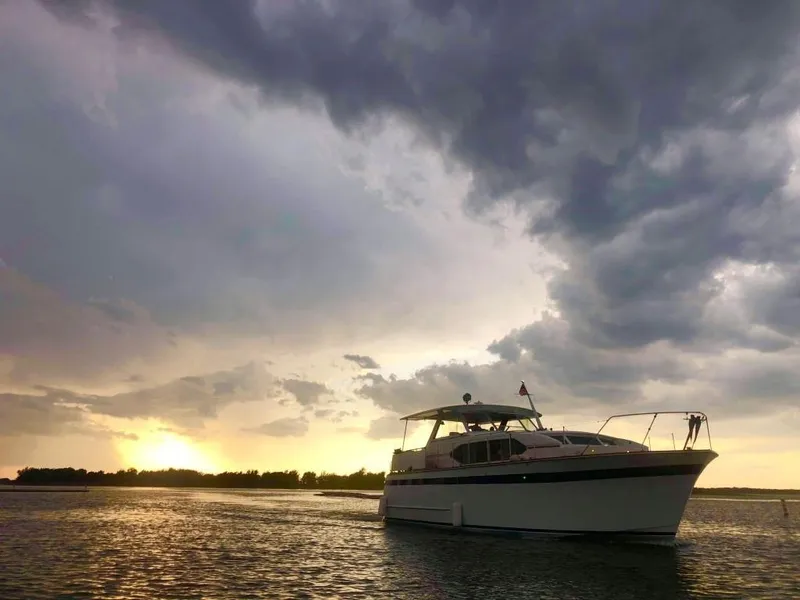 Slide: The Image of 1969 Chris-Craft 46 Roamer yacht on water at sunset with dramatic clouds. - 14