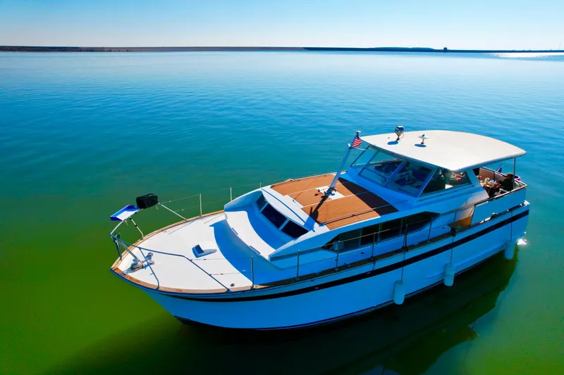 Slide: The Image of 1969 Chris-Craft 46 Roamer yacht on calm, clear water under a bright blue sky. - 16